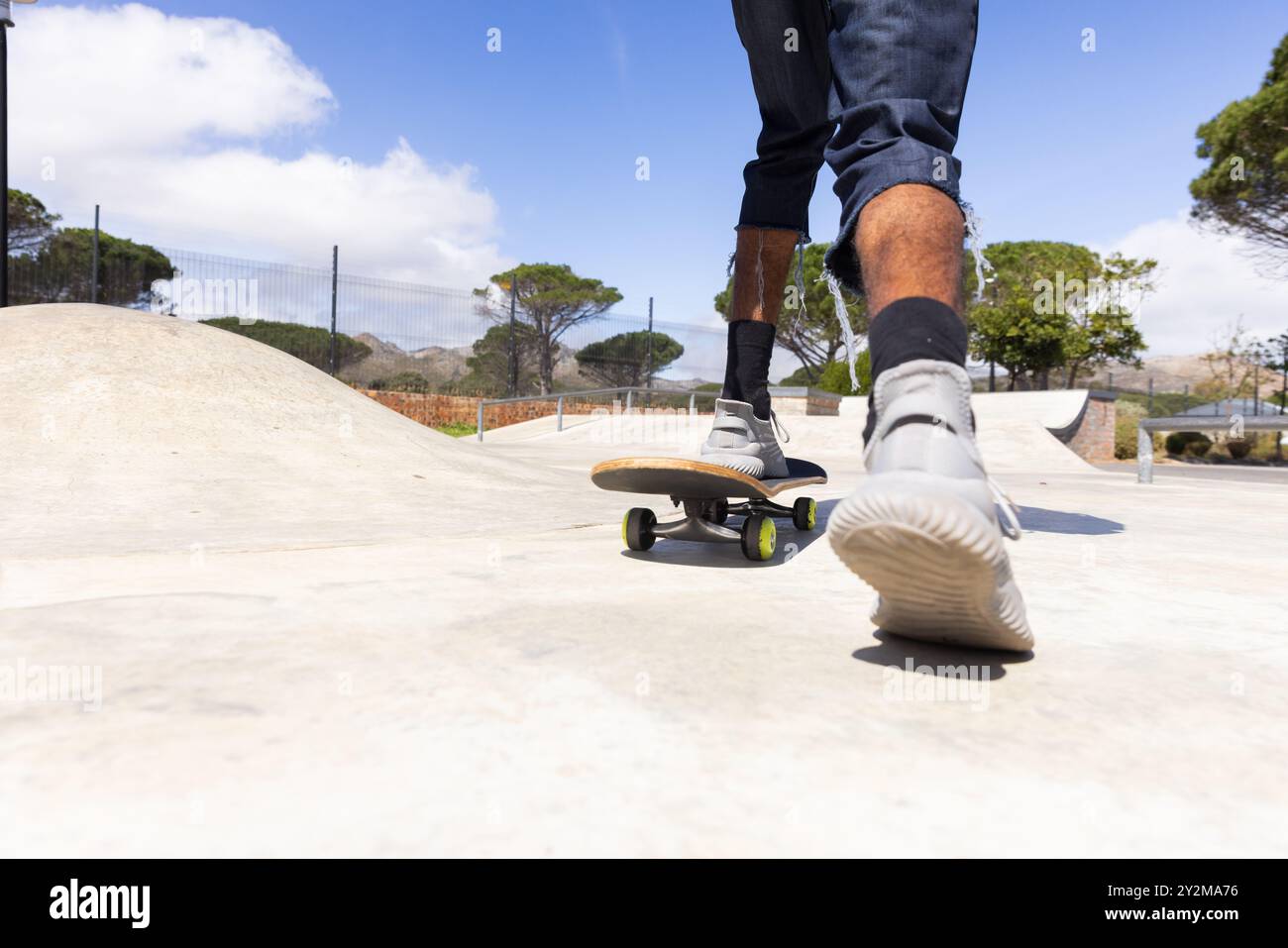 All'aperto, skateboard, adolescente afroamericano che indossa scarpe da ginnastica e jeans che si divertono Foto Stock