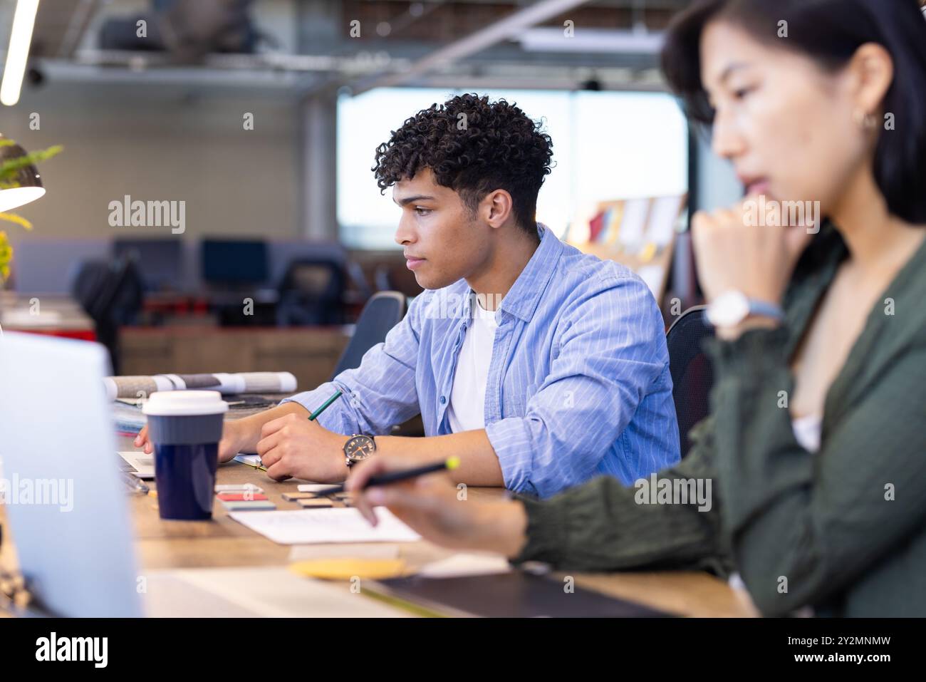In ufficio, progettando spazi interni, un uomo concentrato che lavora al laptop e prende appunti Foto Stock