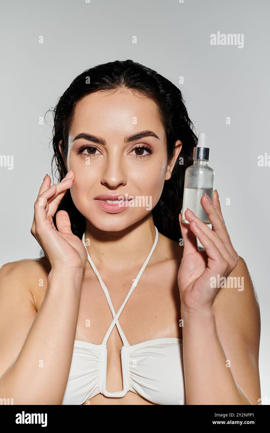 Una giovane donna dimostra felicemente la sua routine di cura della pelle con energia vibrante. Foto Stock