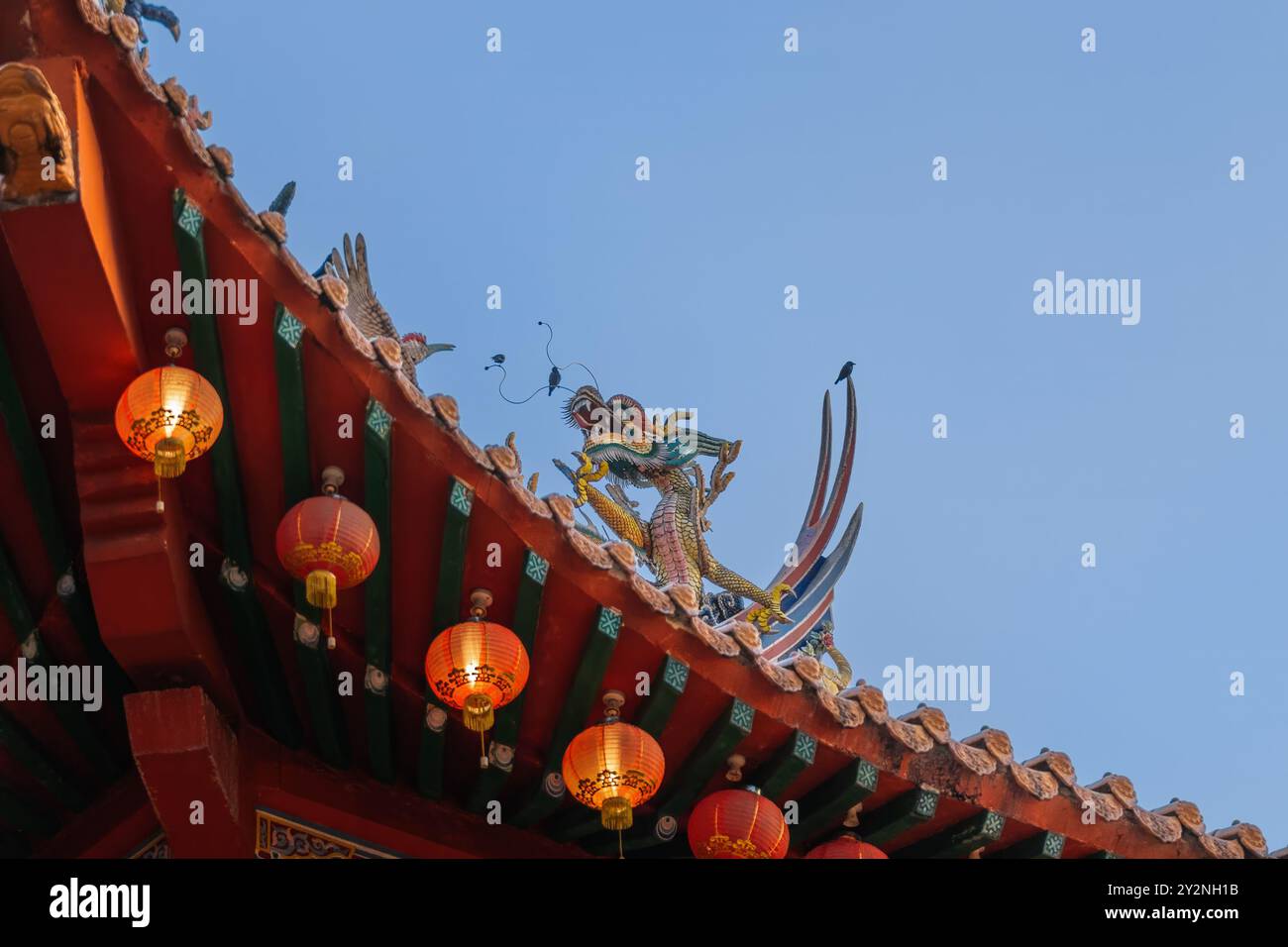 Vibrante scultura cinese del drago sul tetto del tempio con lanterne rosse. Foto Stock