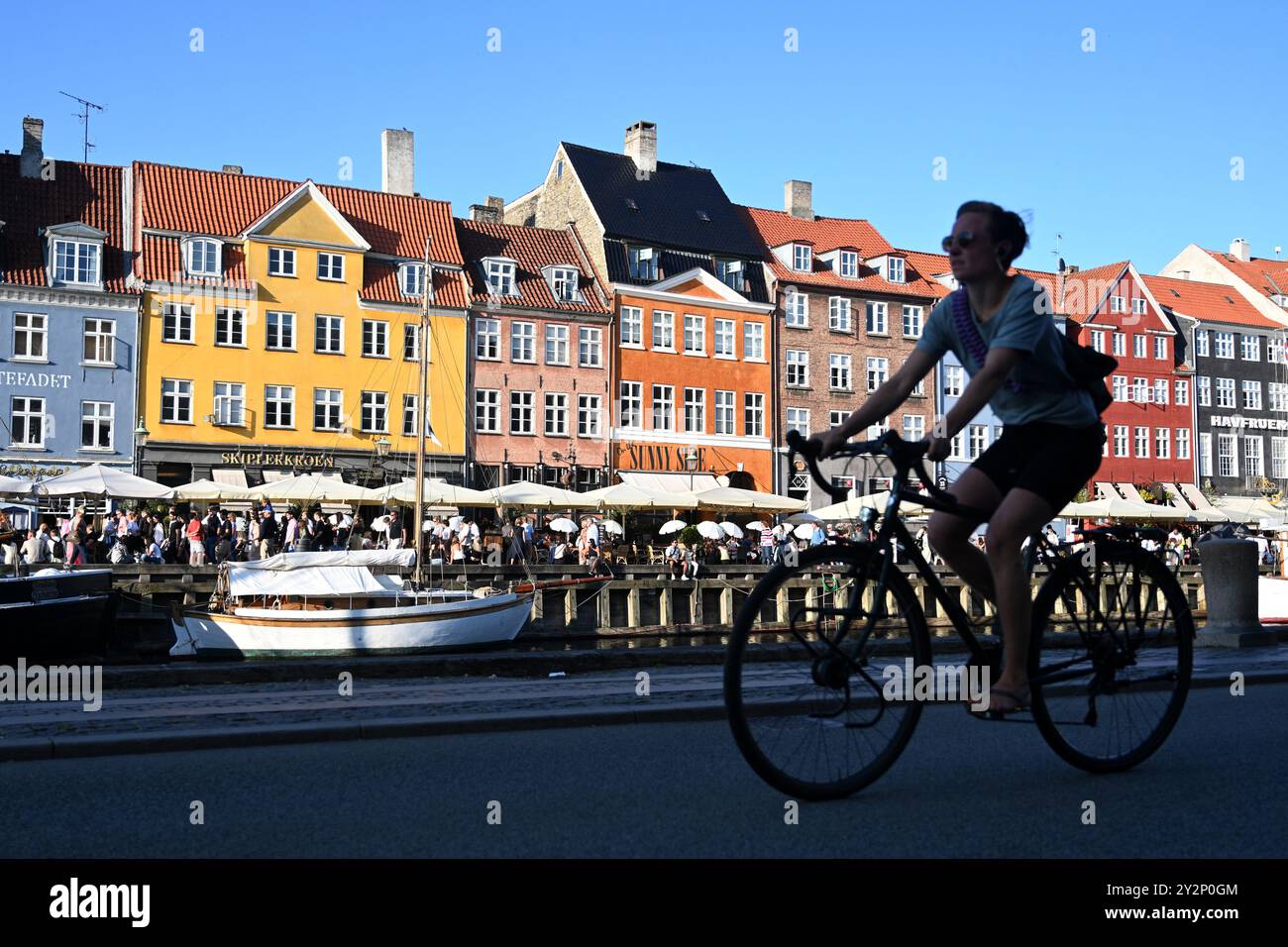 Copenaghen, Danimarca - 31 luglio 2024: Un ciclista sul lungomare di New Harbour (Nyhavn), canale e quartiere dei divertimenti a Copenaghen, Danimarca. Foto Stock