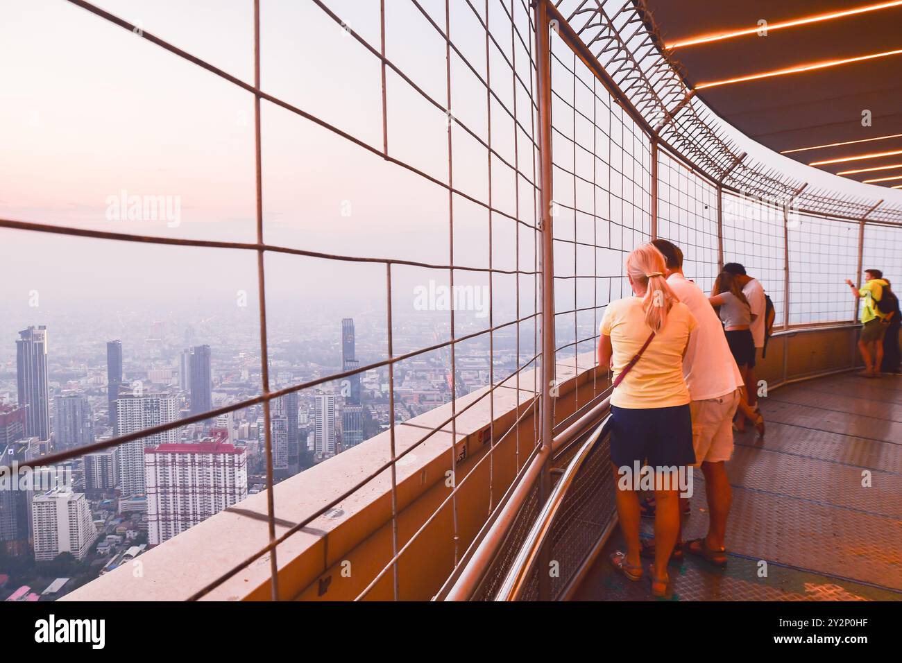 Bangkok, Tailandia - 25 marzo 2024: Famiglia turistica caucasica godetevi il tramonto sullo skyline di Bangkok dalla piattaforma di osservazione girevole con vista del cielo di Baiyoke Foto Stock