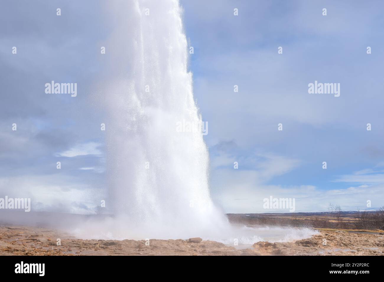 I turisti si meravigliano di fronte all'eruzione del geyser Strokkur, che invia un pennacchio di vapore e acqua in alto nell'aria. Questa meraviglia geotermica è un'attrazione popolare Foto Stock