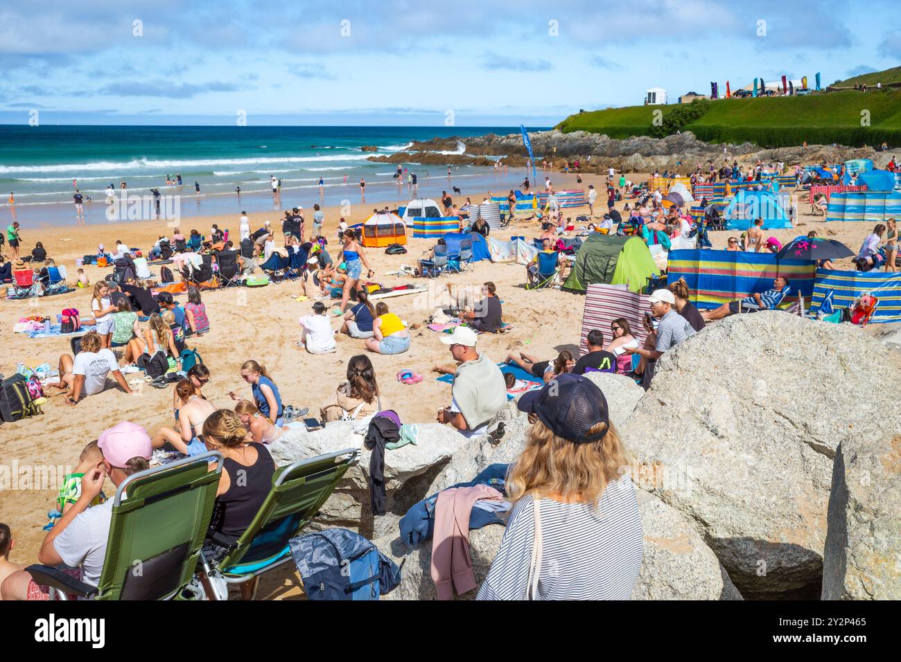 Turisti che si godono il sole estivo sull'iconica spiaggia Fistral di Newquay, in Cornovaglia, nel Regno Unito. Foto Stock