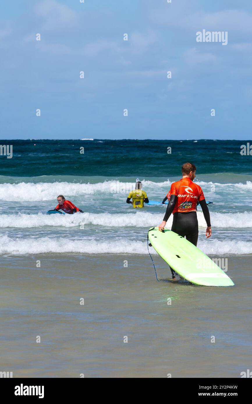 Principianti di surf che tengono una lezione di surf con istruttori del NQY Activity Centre di Towan Beach a Newquay in Cornovaglia nel Regno Unito. Foto Stock