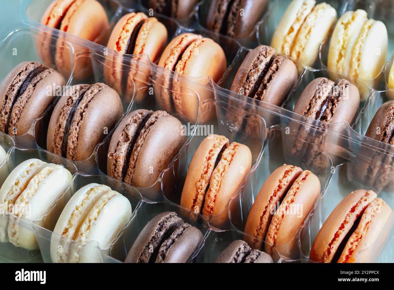 Vista sul tavolo di una serie di macaron francesi aromatizzati. Bianco, latte e cioccolato fondente con aromi arancioni. Foto Stock