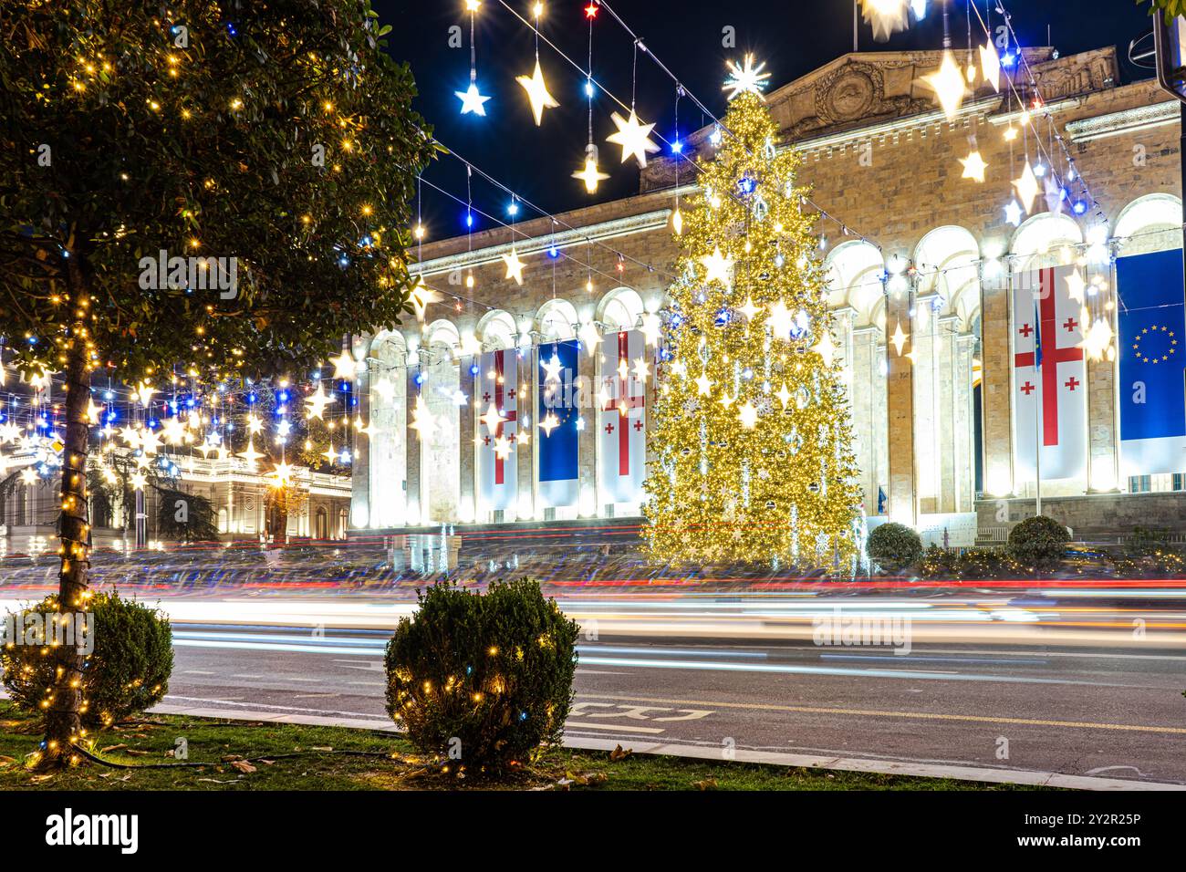 Le luci natalizie abbracciano l'architettura di Tbilisi, Georgia, con un grande albero e stelle scintillanti. Foto Stock