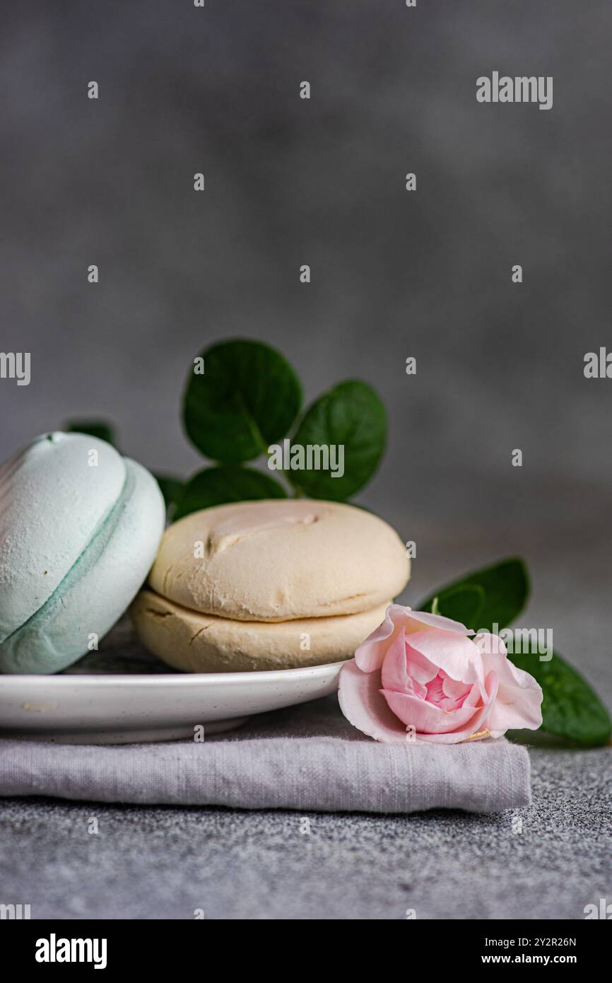 Una composizione squisita con macaron color pastello abbinati a una delicata rosa, sullo sfondo testurizzato per un dis raffinato e invitante Foto Stock