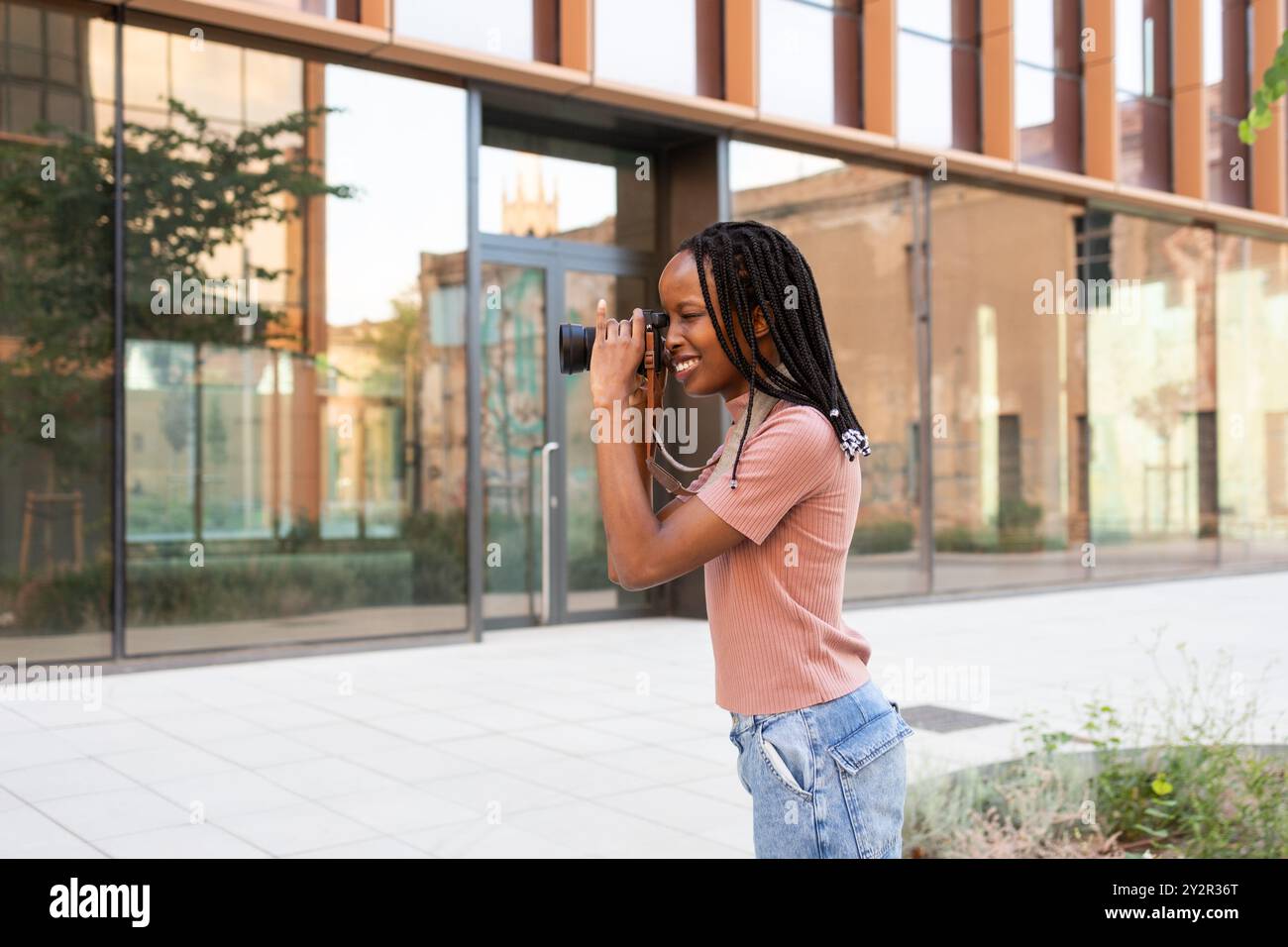 Una giovane studentessa gioiosa utilizza una fotocamera digitale per catturare immagini nel suo campus universitario, mostrando il suo entusiasmo e la sua creatività in una modalità Foto Stock
