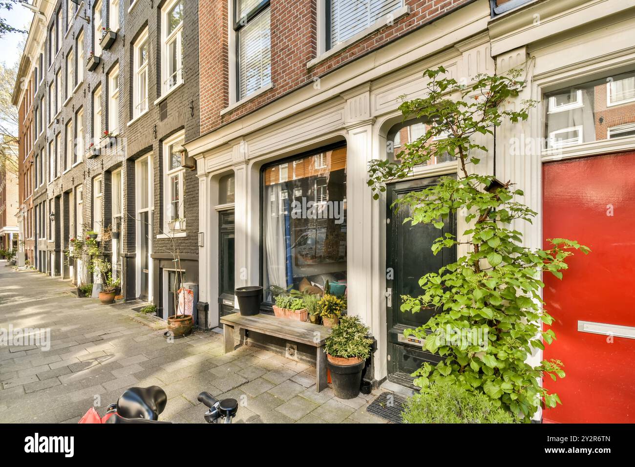 Pittoresca strada europea con case tradizionali colorate adornate con piante e una bicicletta in primo piano. Foto Stock