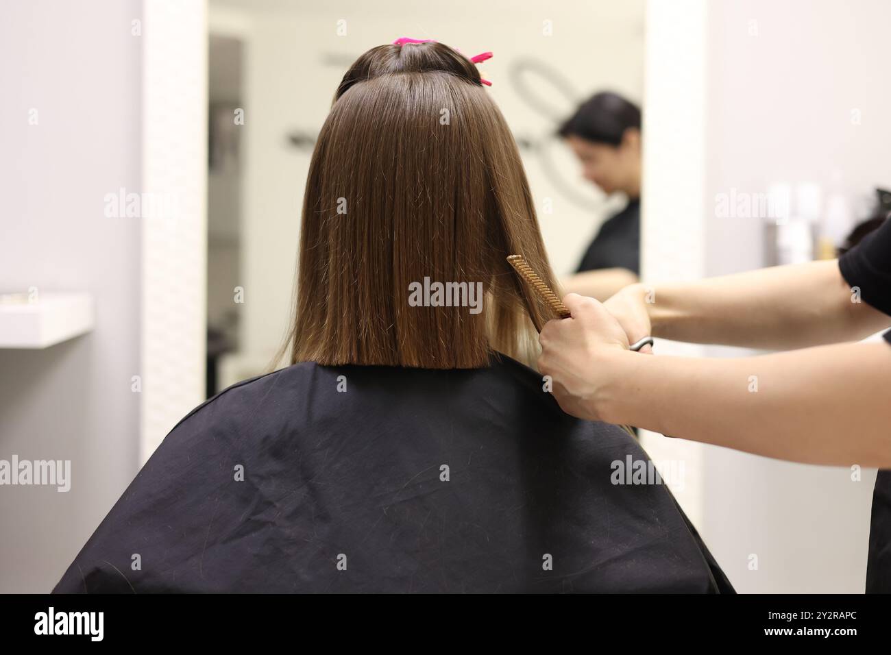 Irriconoscibile parrucchiere che taglia i capelli delle clienti femminili con forbici da barbiere e pettine professionali e crea un'elegante acconciatura corta in bea Foto Stock