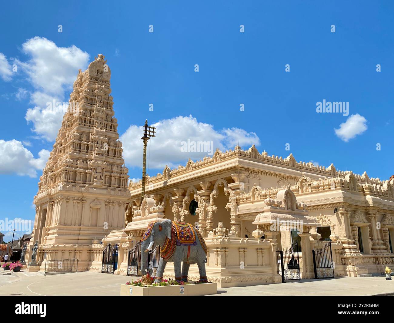 Un tempio indù splendidamente dettagliato con un cielo azzurro e una statua di un elefante di fronte Foto Stock