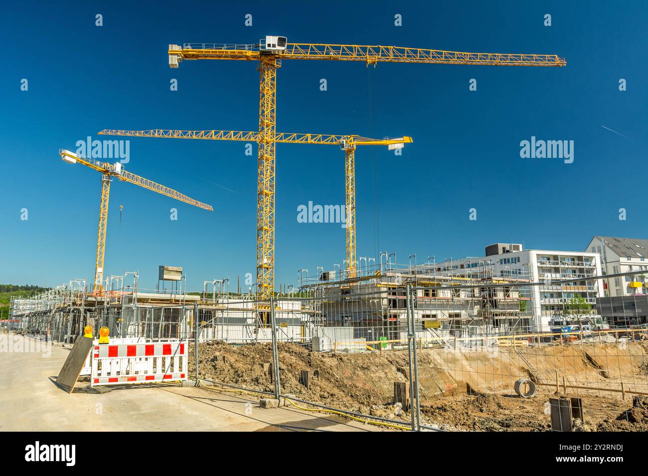 Grande cantiere con gru, fondazioni di recinzioni ed edifici non finiti Foto Stock