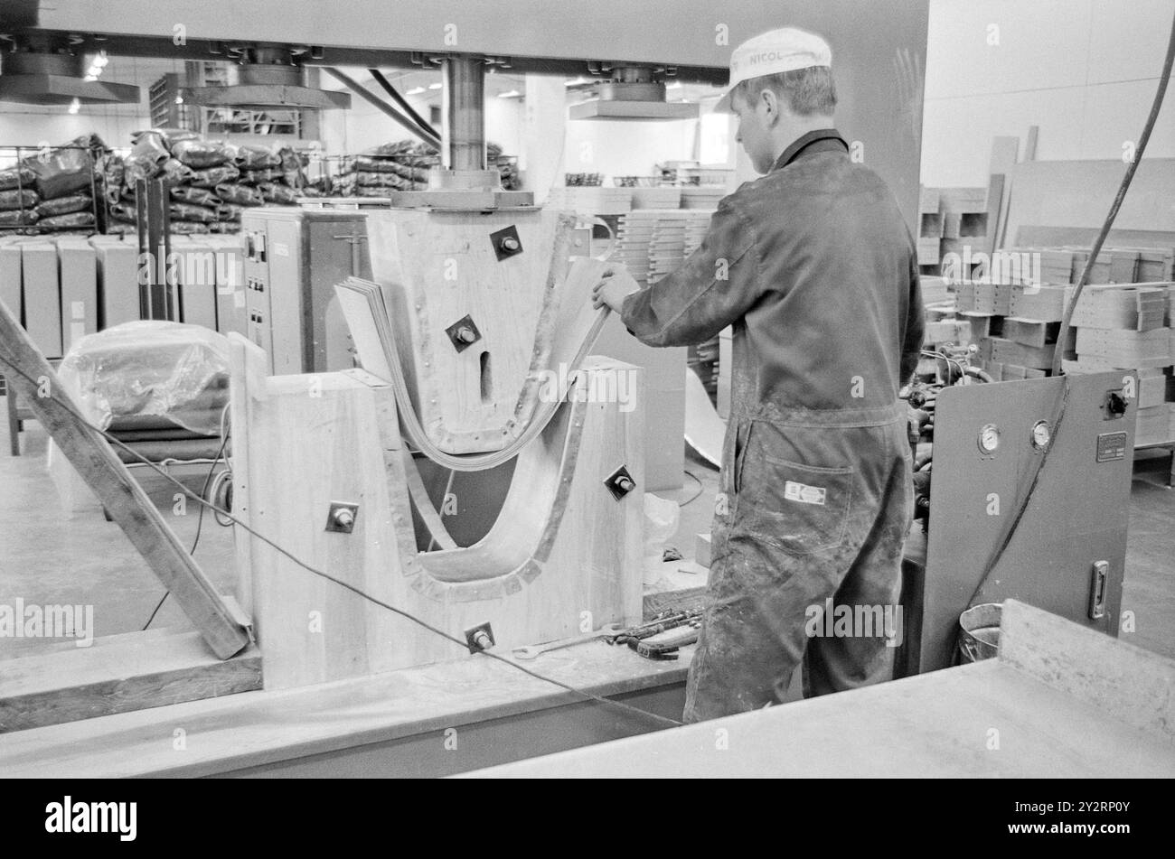 Effettivo 52-3-1971: Clima duro per mobili. L'industria norvegese dei mobili è entrata in un clima più duro. Le importazioni di mobili aumentano di anno in anno. La concorrenza per i clienti si è intensificata. Ci sono persino fabbriche che trovano più redditizio importare le merci dall'estero che produrle loro stesse. Si tratta di una pressa idraulica che lamina l'impiallacciatura sotto diverse tonnellate di pressione. Rimarrai innegabilmente impressionato dalle attrezzature che si trovano in una moderna fabbrica di mobili. I modelli sono fatti per primi, e le macchine dopo! Foto: Sverre A. Børretzen/Aktuell/NTB Foto Stock