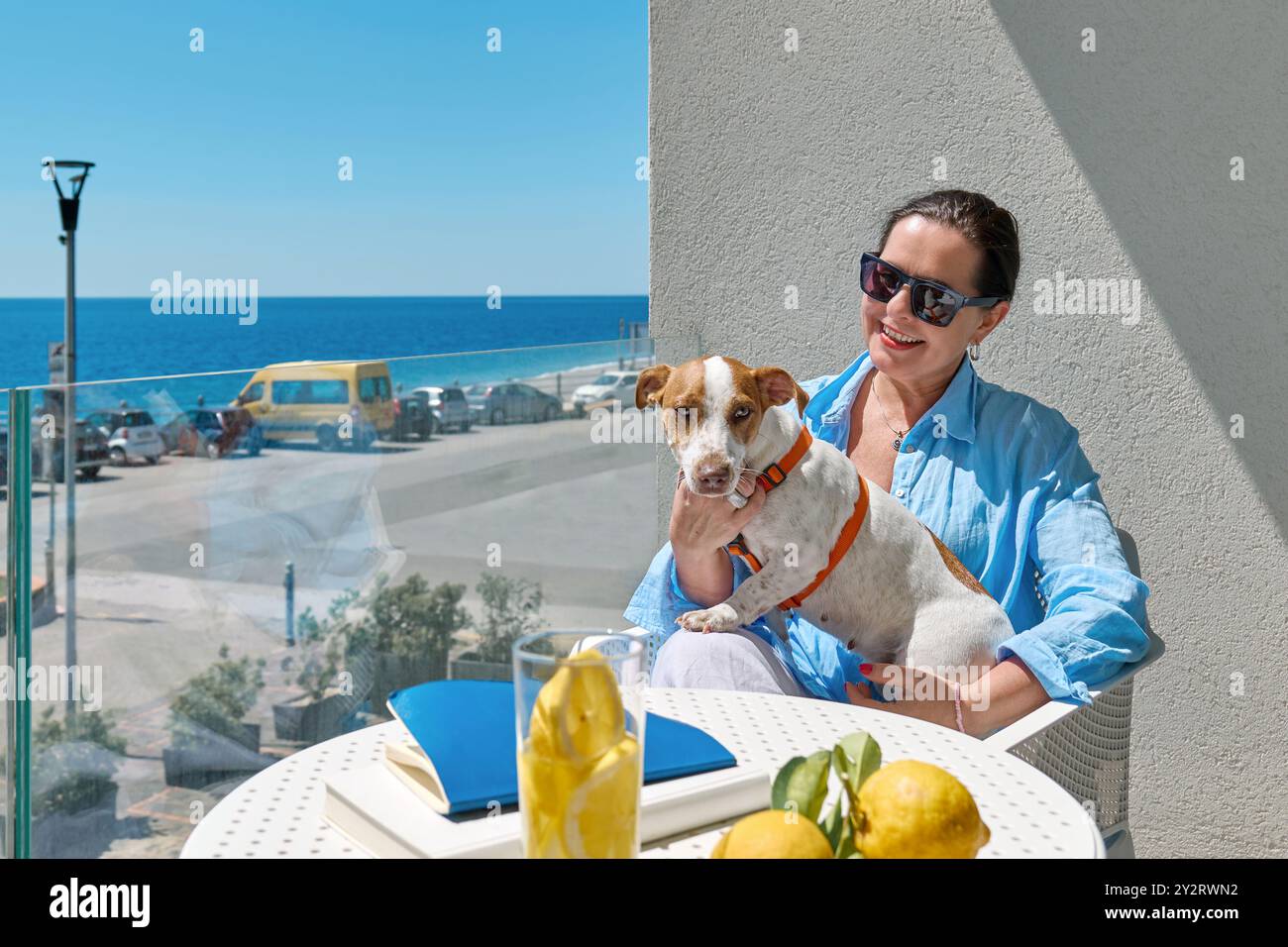 La donna e il suo animale domestico Jack Russell Terrier comunicano nel balcone dell'hotel. Bella donna europea di mezza età e il suo cane passano del tempo insieme. Cane f Foto Stock La donna e il suo animale domestico Jack Russell Terrier comunicano nel balcone dell'hotel. Bella donna europea di mezza età e il suo cane passano del tempo insieme. Cane f Foto Stock