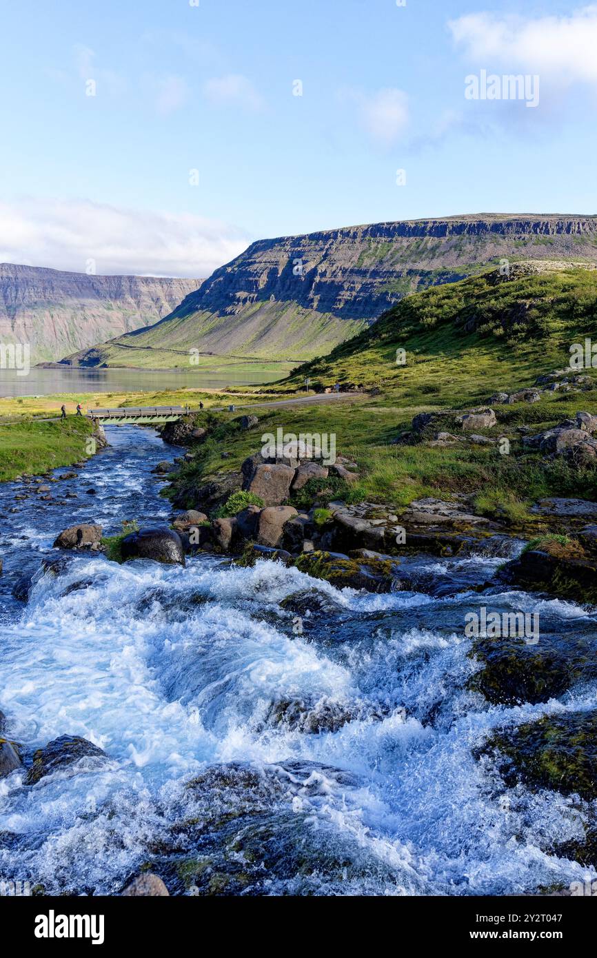 Vista da una delle cascate più piccole sotto Dynjandi alla baia di Dynjandisvogur e alle montagne circostanti. Arnarfjörður, Westfjords, Islanda Foto Stock