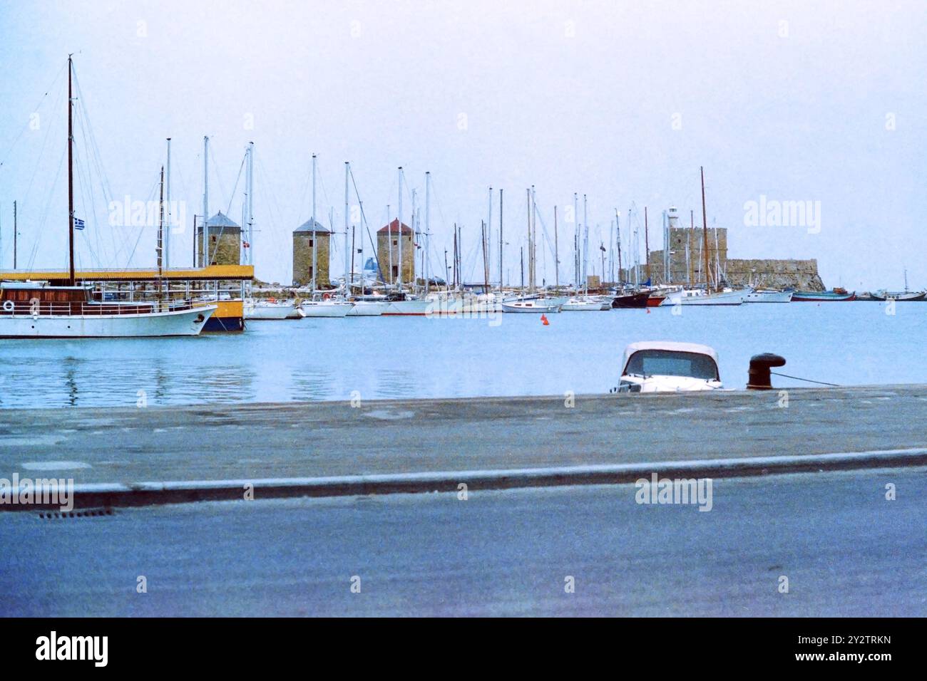 Mulini a vento Mandraki e Colossus di Rodi con yacht. Presa nel 1983. Scansione e conversione pellicola negativa da 35 mm. 1980 anni Foto Stock