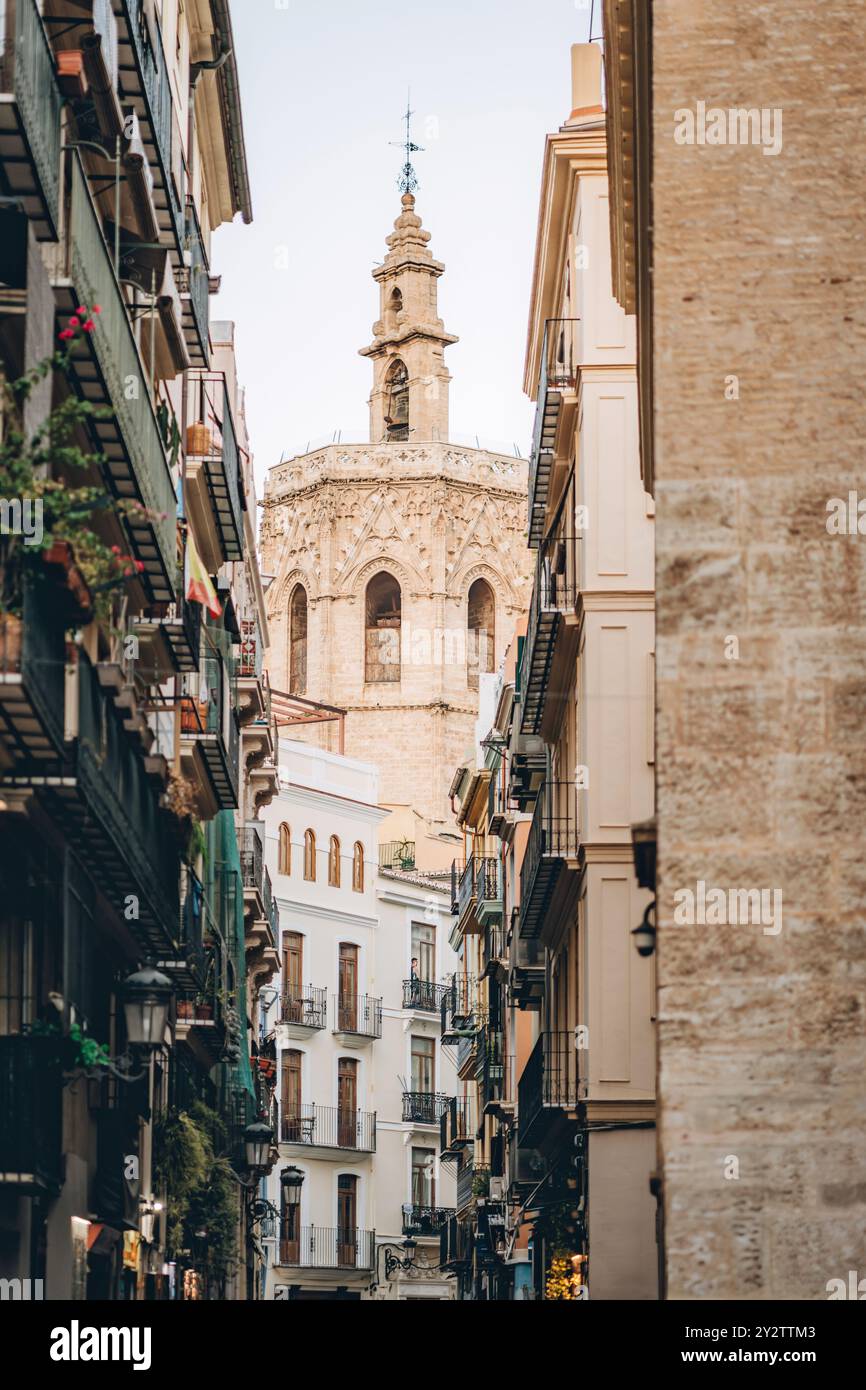 Una strada stretta affascinante e affascinante che mostra una bellissima e storica torre nel cuore di Valencia Foto Stock