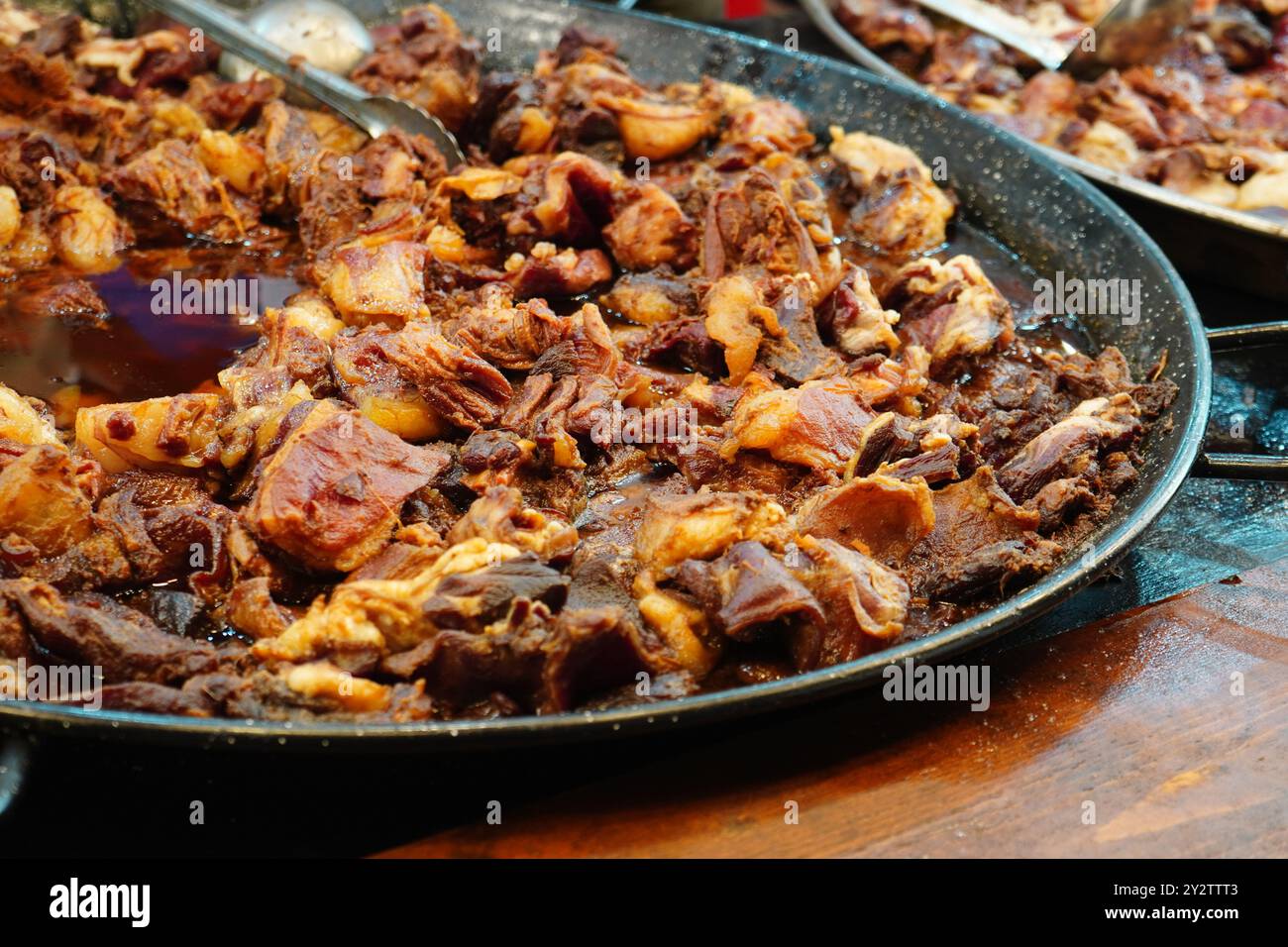 Pezzi di carne di maiale fritti nel grasso in padelle metalliche alla tradizionale fiera rumena del cibo di strada a Bucarest Foto Stock