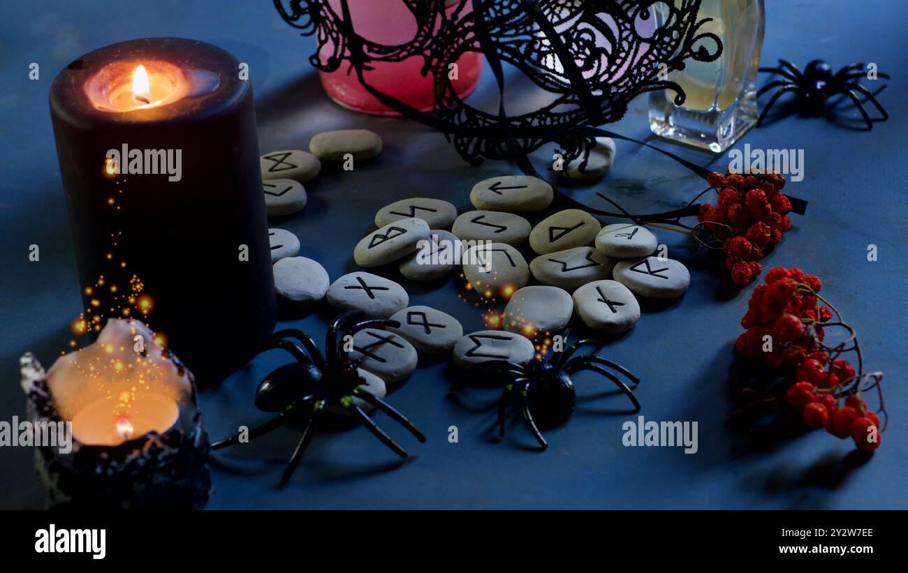 Rune su un tavolo, candele, ragni, maschera nera, frutti di bosco di rowan. Foto Stock