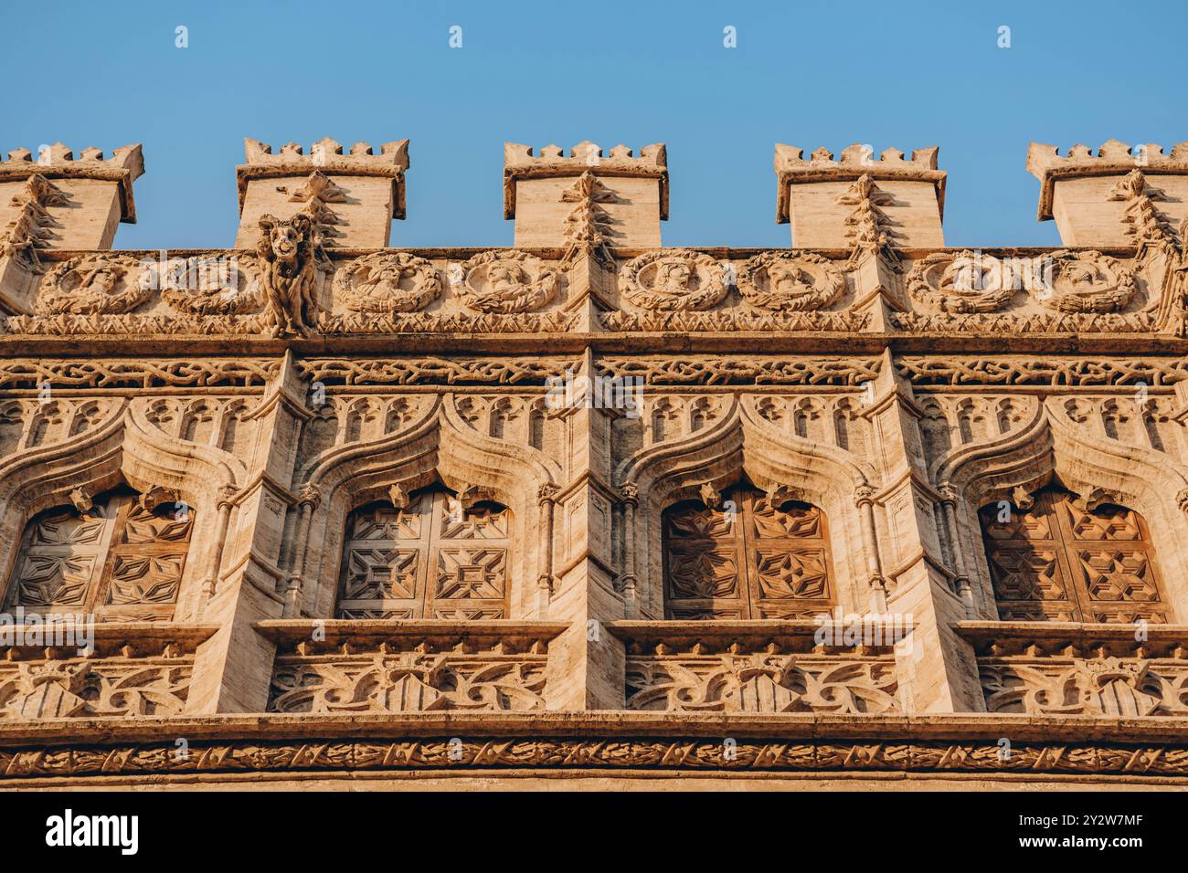 Esplora le splendide incisioni e l'architettura dettagliata di questa facciata storica sotto il cielo azzurro di Valencia, Spagna Foto Stock