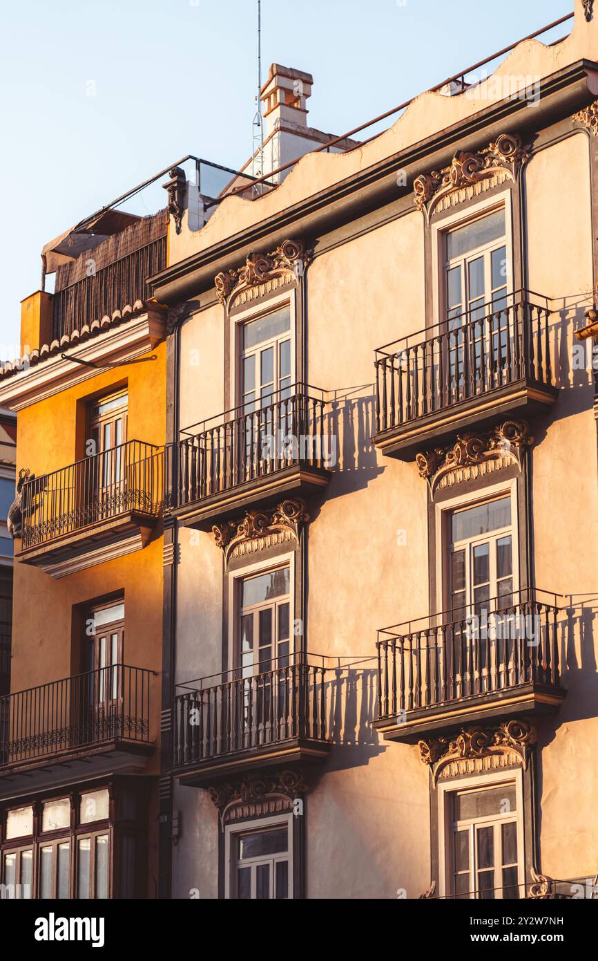 Un edificio storico splendidamente illuminato mette in mostra intricati e artistici balconi in un affascinante ambiente urbano a Valencia, Spagna Foto Stock