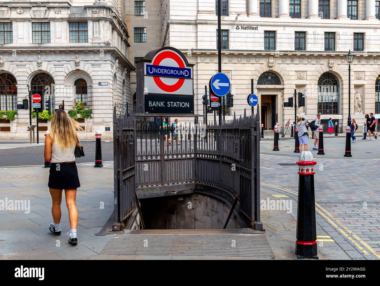 Una donna che cammina oltre l'ingresso di Queen Victoria Street alla stazione della metropolitana Bank nella City di Londra, Londra, Regno Unito Foto Stock