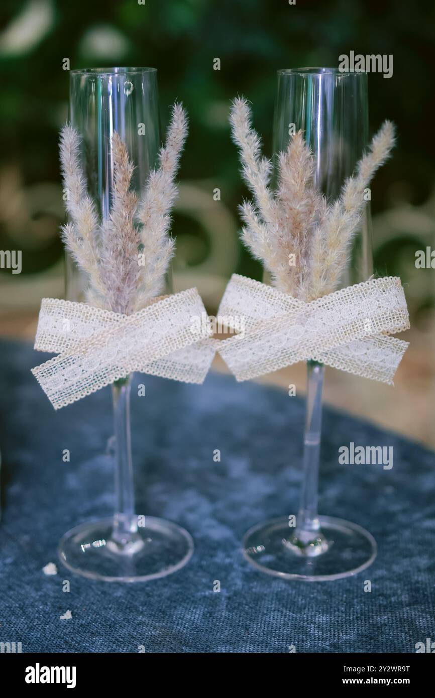 Vista verticale ravvicinata di due flute di champagne decorate su un tavolo blu, con sfondo sfocato Foto Stock