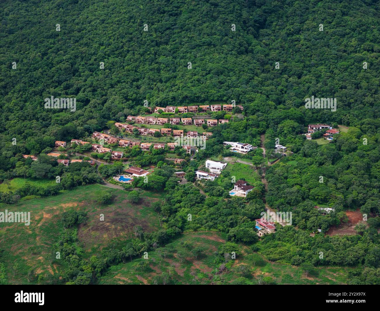 Residenziale con piscina sullo sfondo verde di una collina, vista aerea dei droni Foto Stock