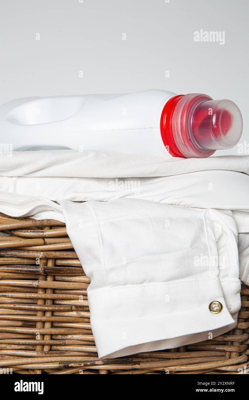Cestino per bucato pieno di vestiti bianchi piegati, mockup con bottiglia di detergente, giorno del bucato e cura dell'abbigliamento Foto Stock
