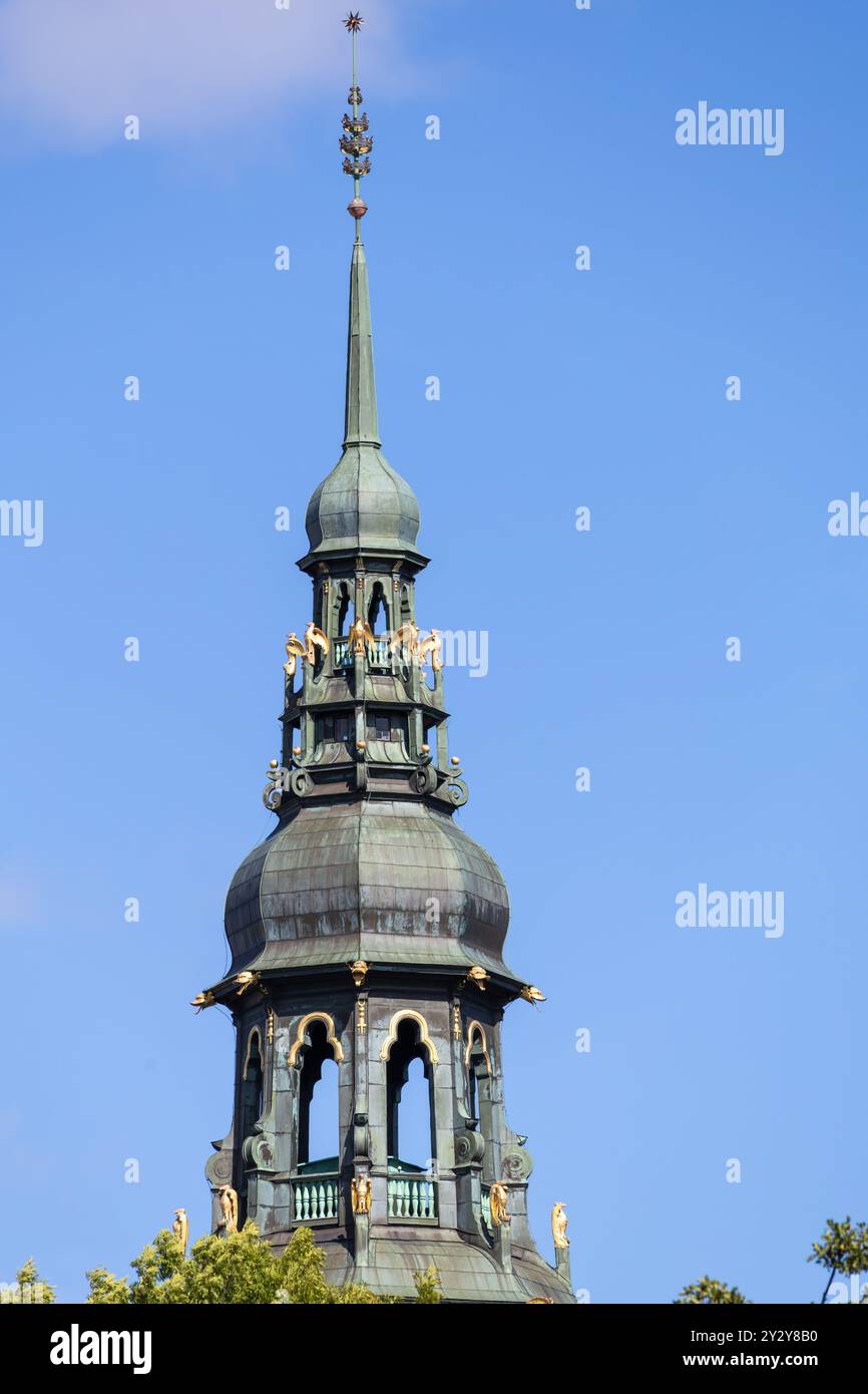 Una vista ravvicinata di una storica torre della chiesa con una cupola di rame verde e dettagli ornati su un cielo azzurro. Foto Stock