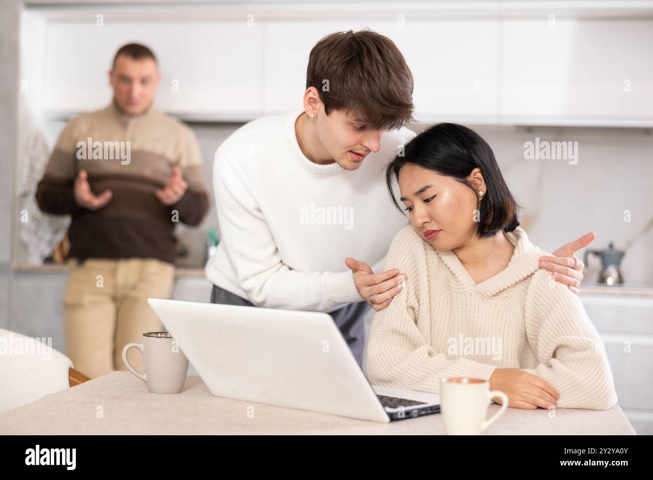 Un ragazzo convince una giovane ragazza a smettere di giocare ai videogame. Padre turbato in sottofondo Foto Stock