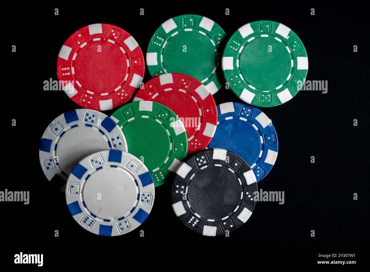 Le chip di poker di tutti i colori vengono posizionate in modo casuale su uno sfondo nero Foto Stock