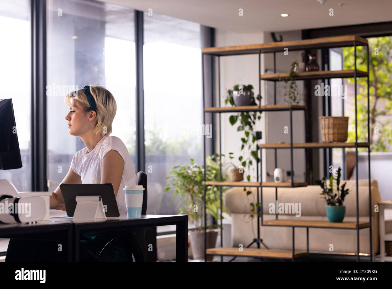 Lavora alla scrivania, donna che si concentra sul computer in un ambiente d'ufficio moderno Foto Stock