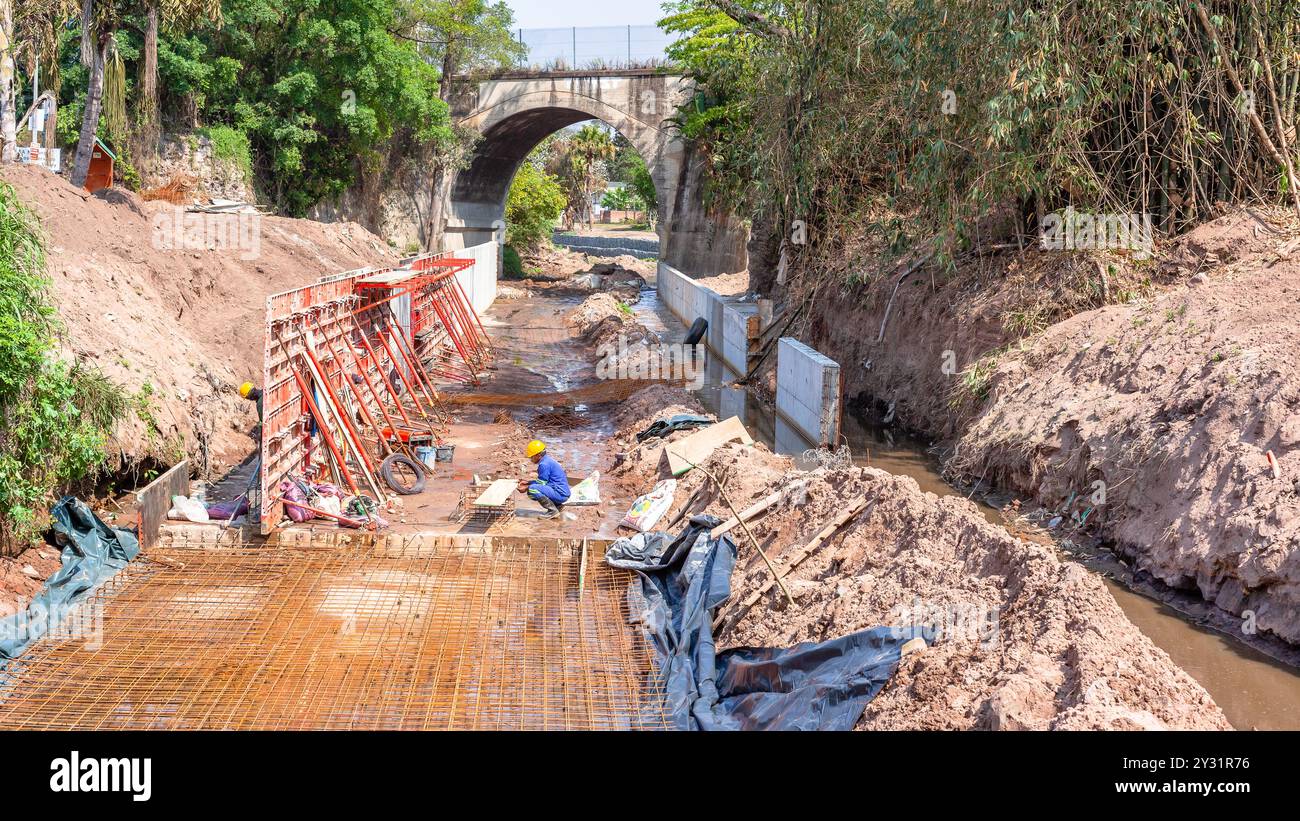 La costruzione del canale fluviale in acciaio industriale, le pareti in cemento modellano l'edificio in corso per le tempeste meteorologiche che guidano le inondazioni d'acqua attraverso la campagna Foto Stock