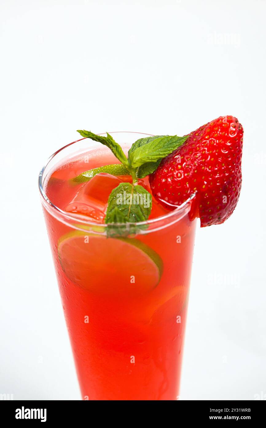Splendido cocktail di fragole con ghiaccio, decorato con fragole fresche e menta, su un tavolo bianco. cocktail di fragole isolato su sfondo bianco Foto Stock