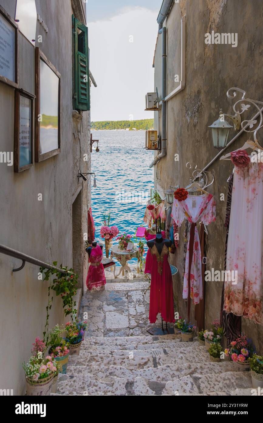 Rovigno Croazia 27 agosto 2024, percorrendo un pittoresco vicolo di Rovigno, gli abiti vibranti oscillano dolcemente nella brezza, circondati da fiori lussureggianti e. Foto Stock