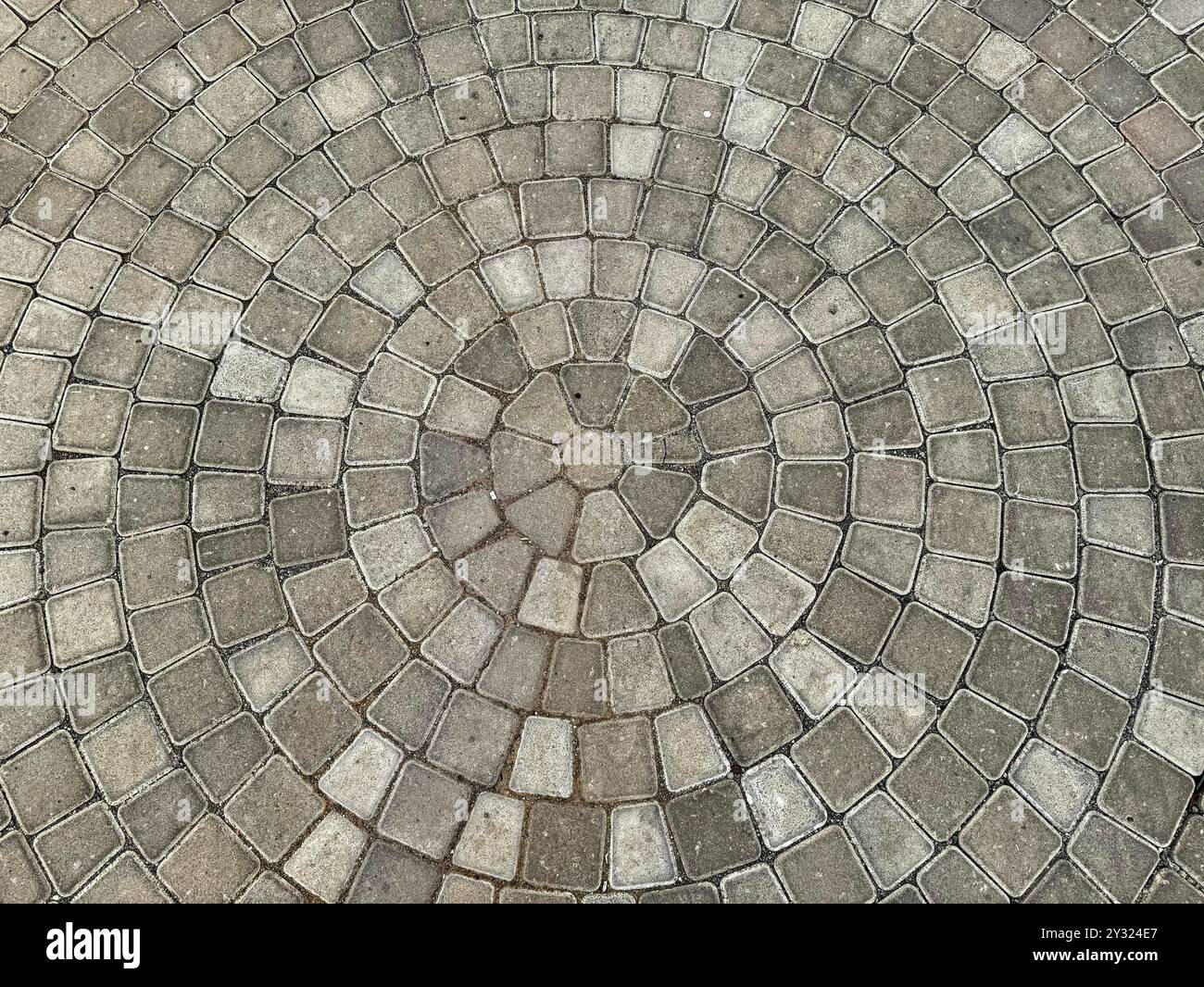 Ciottoli grigi naturali o lastre di pietra per pavimentazione che formano un motivo circolare per rifiniture di pavimenti da giardino all'aperto. Foto Stock Ciottoli grigi naturali o lastre di pietra per pavimentazione che formano un motivo circolare per rifiniture di pavimenti da giardino all'aperto. Foto Stock