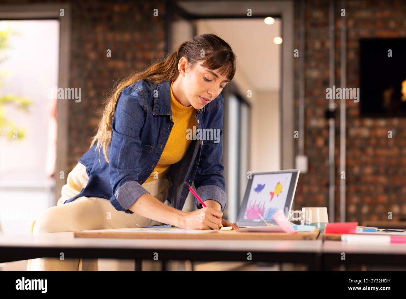 Scrivi appunti, donna che lavora a progetti creativi con un portatile in un ufficio moderno Foto Stock