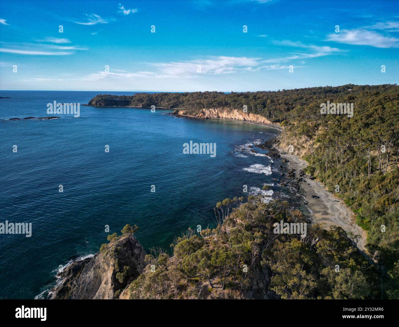 Vista aerea di un paesaggio costiero con acque cristalline e lussureggianti scogliere boscose verdi. Foto Stock