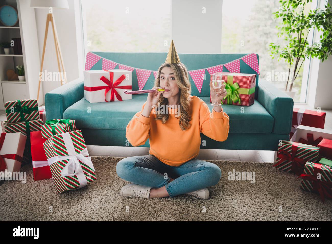 Foto a figura intera di una bella ragazza allegra sedersi per festeggiare il compleanno vestiti di arancio eccitati passare il passatempo casa spaziosa al coperto Foto Stock