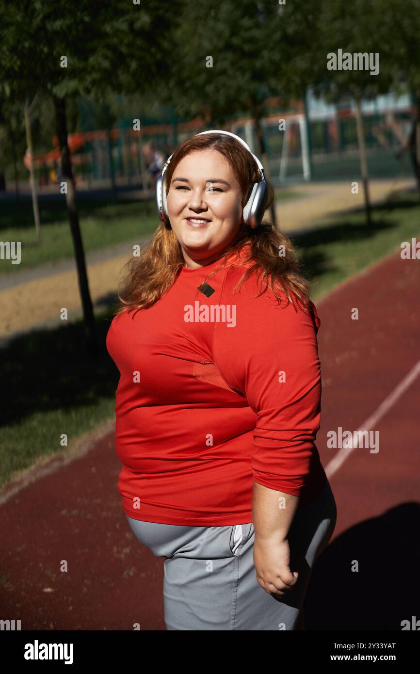 Una donna gioiosa ama fare esercizio in un'atmosfera vivace del parco. Foto Stock