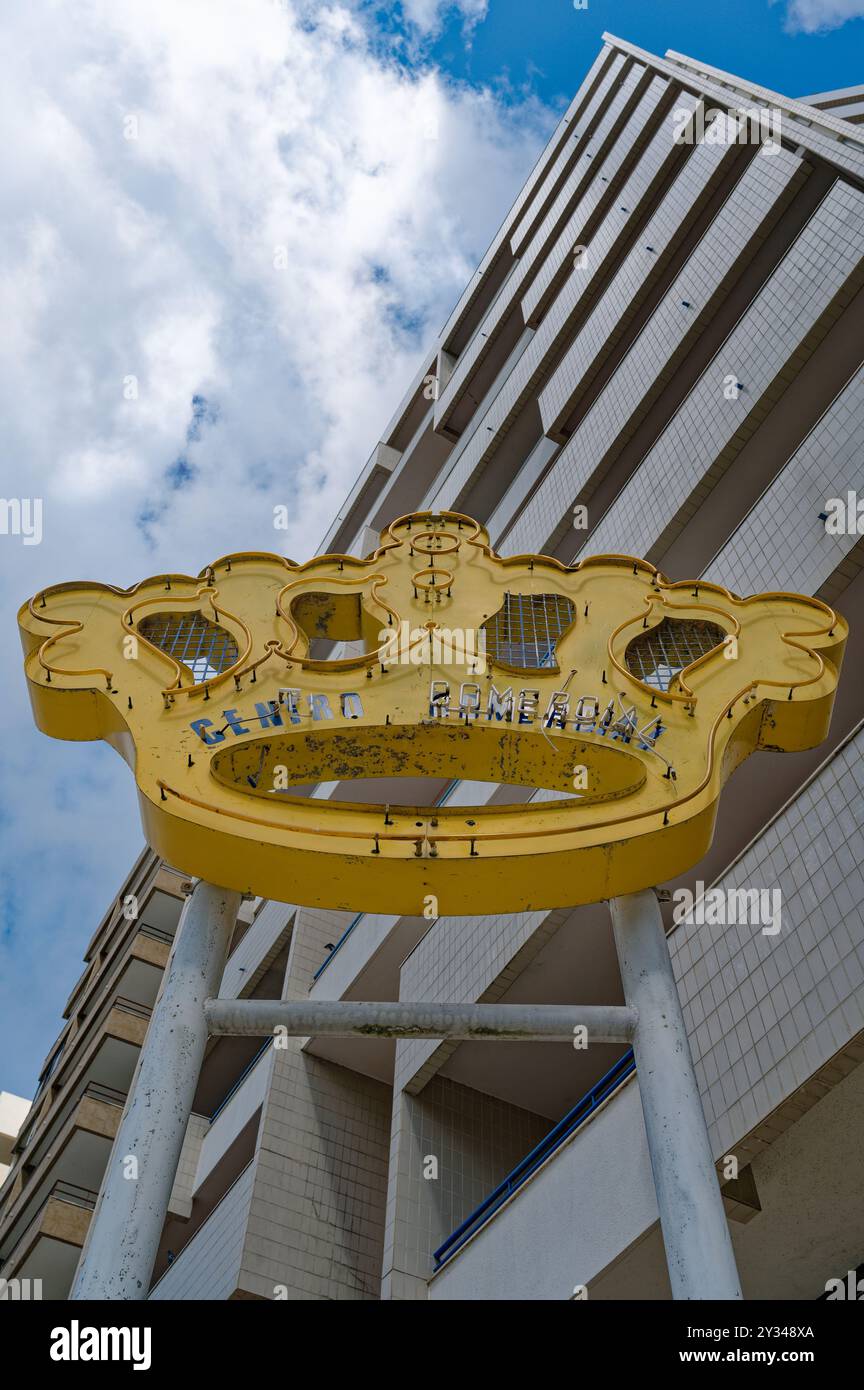 Un segno giallo intemprato a forma di corona si erge alto, leggendo 'Centro Comercial' in lettere sbiadite Foto Stock