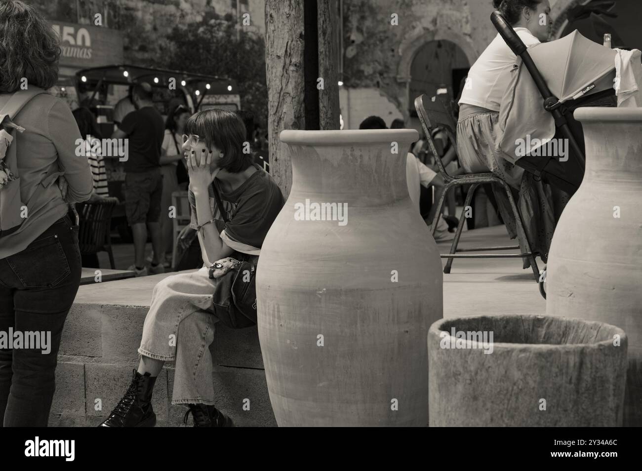 Monocromatico di una giovane donna seduta con cura da grandi piantagioni di terracotta nel centro culturale 8 Marvila Foto Stock