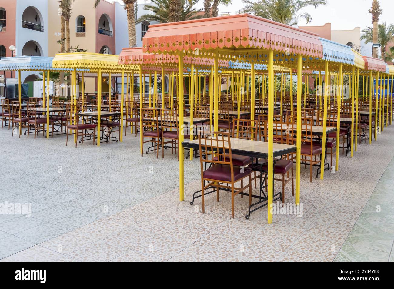 Terrazza ristorante esterna in legno con tavoli con quattro posti a sedere con un piccolo tetto contro il sole Foto Stock