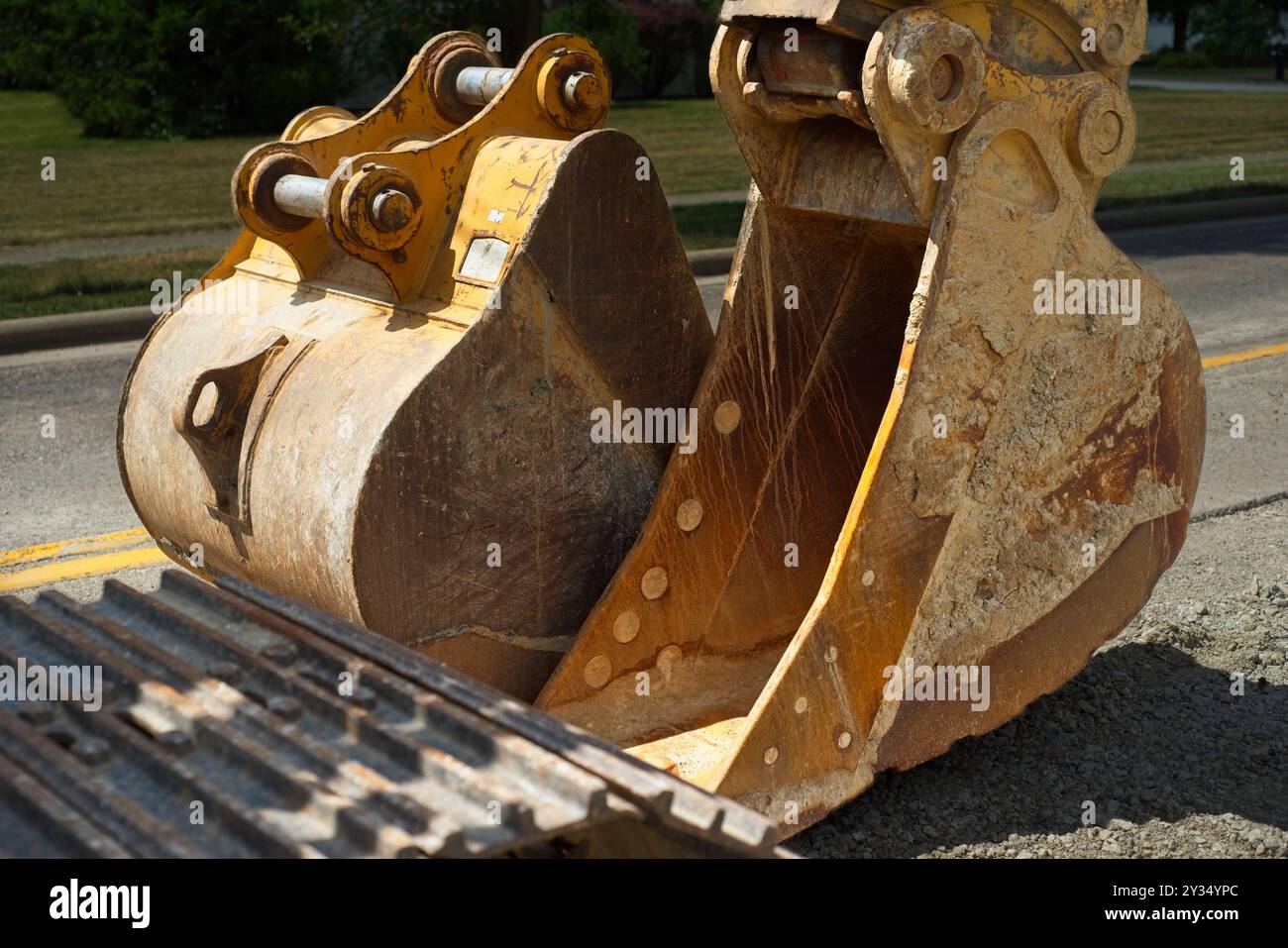 Primo piano delle benne doppie per un escavatore per la costruzione di strade, quella sinistra non collegata Foto Stock
