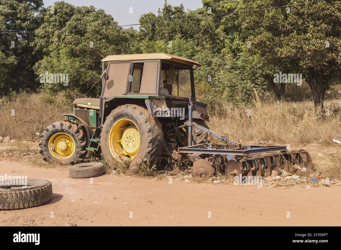 Vecchio trattore arrugginito abbandonato su una strada sterrata in Gambia Foto Stock