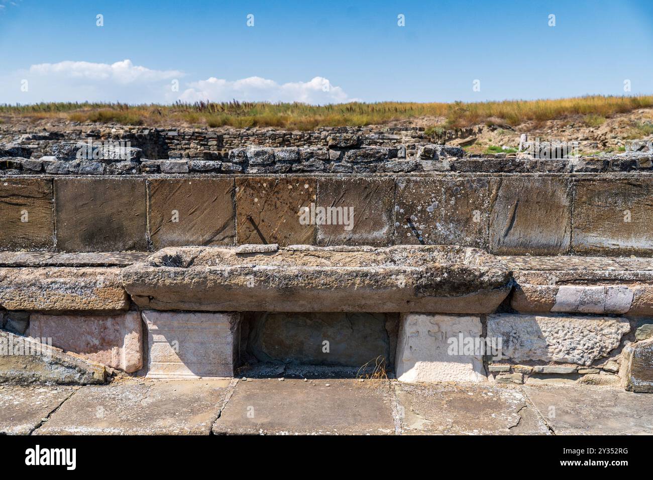 Resti dell'antica fontana: Parte della città macedone di Stobi dal 359 a.C., contro un cielo blu con nuvole. Foto Stock