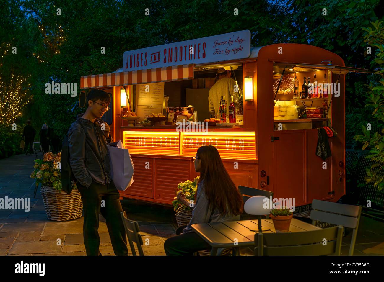 Una coppia che aspetta un drink al Bicester Village. Una popolare destinazione per lo shopping, con boutique di marca di lusso in un villaggio in stile New England. Foto Stock