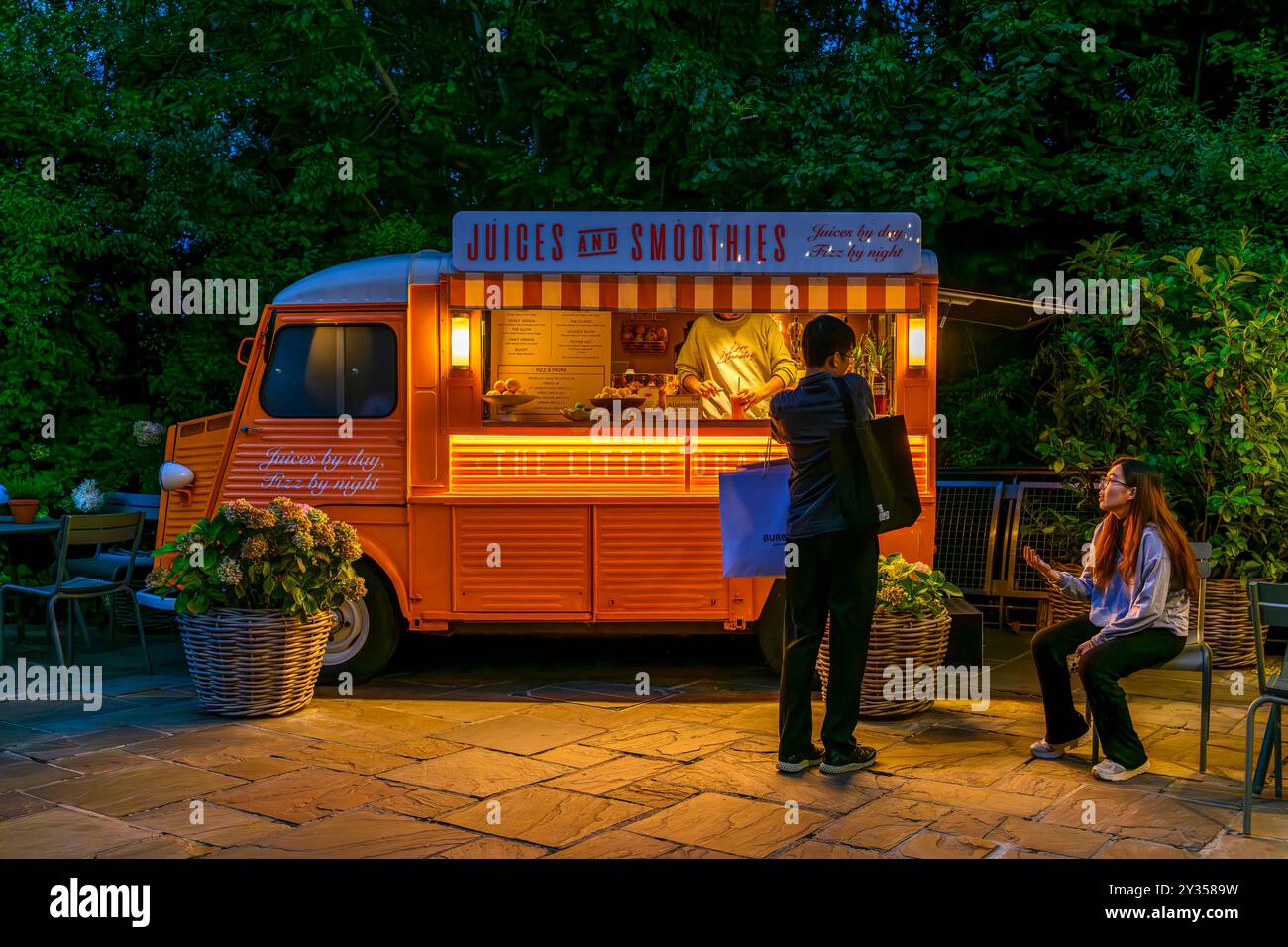 Una coppia che aspetta un drink al Bicester Village. Una popolare destinazione per lo shopping, con boutique di marca di lusso in un villaggio in stile New England. Foto Stock